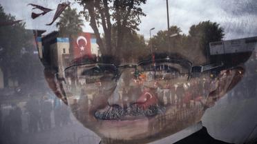 Photo prise à travers une banderole électorale tranparente affichant un portrait du Premier ministre turc Ahmet Davutoglu le 29 octobre 2015 à Istanbul [DIMITAR DILKOFF / AFP]