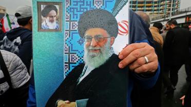 Un Iranien brandit une affiche avec le portrait du guide suprême Ali Khamenei (centre) et de l'ayatollah Rouhollah Khomeiny, père fondateur de la République islamique (en haut à gauche), lors du 40e anniversaire de la Révolution islamique à Téhéran, le 11 février 2019 [ATTA KENARE / AFP]