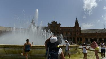 Des personnes se rafraîchissent dans une fontaine de Séville, le 1er août 2018 en Espagne [CRISTINA QUICLER / AFP]