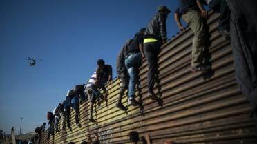 Des migrants centraméricains grimpent sur la barrière métallique marquant la frontière entre le Mexique et les Etats-Unis à Tijuana, le 25 novembre 2018 [Pedro PARDO / AFP]