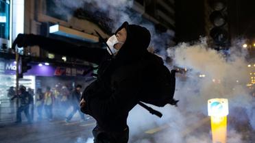 Un manifestant dans un nuage de gaz lacrymogènes tiré par la police, le 25 décembre 2019 à Hong Kong [Philip FONG / AFP]