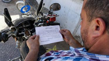 Un Syrien lit un tract portant le sceau des forces gouvernementales et appelant la population à "rejoindre le (processus de) réconciliation" à Binnish, dans le nord-ouest de la Syrie, le 9 août 2018 [OMAR HAJ KADOUR / AFP]