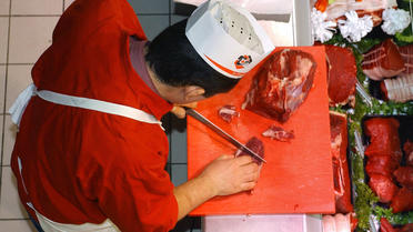 Un boucher découpe une piéce de boeuf au rayon boucherie d'un Intermarché, de Chalonnes-sur-Loire, en décembre 2004 [Frank Perry / AFP/Archives]