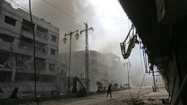 De la fumée et de la poussière s'élèvent d'une rue après des raids aériens du régime syrien sur la localité de Hammourié, dans le fief rebelle de la Ghouta orientale près de Damas, le 21 février 2018  [ABDULMONAM EASSA / AFP]