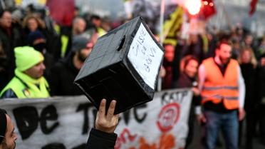 Un homme tient une caisse pour soutenir les grévistes, dans une manifestation à Paris le 26 décembre 2019 [STEPHANE DE SAKUTIN / AFP/Archives]
