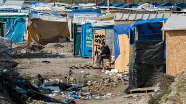 Un homme assis au milieu de cabanes de fortune dans la "Jungle" de Calais, le 16 mars 2016 [DENIS CHARLET / AFP/Archives]