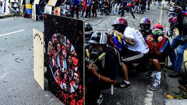Des opposants au régime de Nicolas Maduro se protègent des assauts de la police derrière des boucliers de fortune, le 22 juillet 2017 à Caracas [RONALDO SCHEMIDT / AFP]
