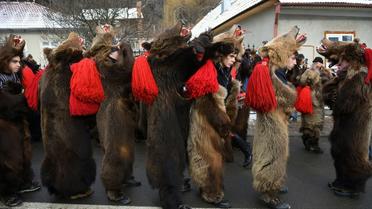Des roumains vêtus de peaux d'ours dansent dans les rues de Comanesti, le 30 décembre 2016 lors d'un défilé pour chasser les mauvais esprits de l'année écoulée [DANIEL MIHAILESCU / AFP]