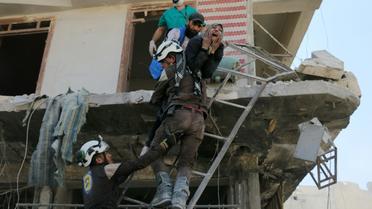 Des bénévoles du service de défense civil syrien évacuent des gens d'un immeuble détruit par des bombardements, dans un quartier rebelle d'Alep le 23 avril 2016 [AMEER ALHALBI / AFP]