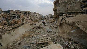 Des Syriens traversent une rue détruite du quartier al-Akroub d'Alep, le 17 décembre 2016 [Youssef KARWASHAN / AFP]
