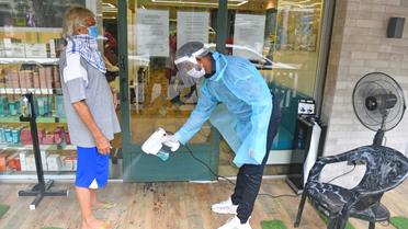 Un employé désinfecte les pieds d'un client avant qu'il entre dans un salon de coiffure, le 28 juin 2020 à Bombay, en Inde [INDRANIL MUKHERJEE / AFP]