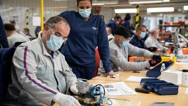 Des employés du groupe automobile PSA assemblent les pièces de respirateurs médicaux, le 15 avril 2020 à l'usine de Poissy, au nord-ouest de Paris [Thomas SAMSON / AFP]