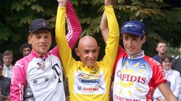 Le vainqueur du Tour de France 1998 Marco Pantani (c) entouré de l'Allemand Jan Ullrich (g) et de l'Américain Bobby Julich (d) sur le podium des Champs-Elysées, le 2 août 1998 à Paris  [Pascal Pavani / AFP/Archives]