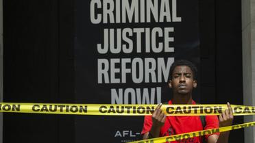 Moah Pollas, pose devant une pancarte peinte près du parc Lafayette, à proximité de la Maison Blanche, à Washington, le 5 juin 2020 [Roberto SCHMIDT / AFP]