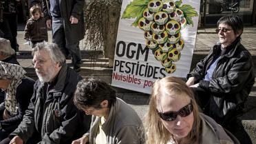Une affiche dénonçant l'usage dangereux des OGM et des pesticides dans l'agriculture et des supporters du viticulteur bio Emmanuel Giboulot le 24 février 2014 à Dijon devant le tribunal où pour avoir refusé de traiter ses vignes  [Jeff Pachoud / AFP/Archives]
