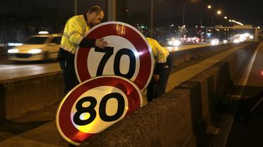 Des employés municipaux changent les paneaux de limitation de vitesse le 7 janvier 2014 sur le boulevard périphérique à Paris [Jacques Demarthon / AFP]
