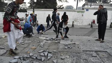Des manifestants brisent des pavés à Alger tandis que la police fait usage de gaz lacrymogène, le 22 février 2019 [RYAD KRAMDI                         / AFP]