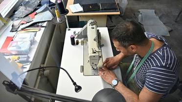 Penché sur sa machine à coudre, le Syrien Khaldoun Alhussain transforme un canot pneumatique en sac ou cabas, dans l'atelier de la petite entreprise mimycri à Berlin [Tobias SCHWARZ / AFP]