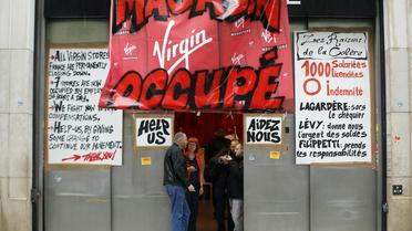 Des personnes se tiennent à l'entrée d'un magasin Virgin occupé par des salariés de l'enseigne, le 17 juin 2013 à Paris  [Francois Guillot / AFP/Archives]