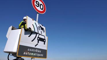 Un ouvrier démonte un panneau annonçant un radar et une limitation de vitesse à 90 km/h [Philippe Huguen / AFP/Archives]
