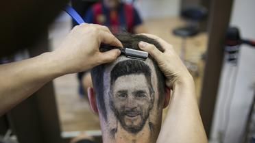 Le coiffeur serbe Mario Hvala dessine Messi sur l'arrière du crâne d'un client à Novi Sad, en Serbie, le 10 juin 2018  [VLADIMIR ZIVOJINOVIC / AFP]