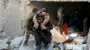Un secouriste syrien porte une femme sauvée des décombres d'un immeuble après des bombardements dans le quartier d'al-Hamra à Alep, tenu par les rebelles, le 20 novembre 2016  [THAER MOHAMMED / AFP]