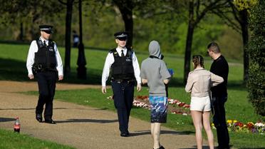 Des policiers s'entretiennent avec des badauds dans le parc Alexandra de Londres, le 10 avril 2020    [Tolga AKMEN / AFP]