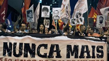 Des Brésiliens militants d'Amnesty International manifestent derrière la bannière "Plus jamais ça", lors du 50e anniversaire du coup d'Etat qui a maintenu le Brésil sous la dictature militaire de 1964 à 1985 à Rio de Janeiro le 1er avril 2014 [Vanderlei Almeida / AFP/Archives]