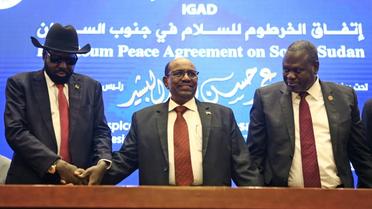 Le président soudanais Omar el-Béchir (C) tient les mains du président sud-soudanais Salva Kiir (G) et du chef rebelle Riek Machar (D) après la signature à Khartoum d'un accord de cessez-le-feu, le 27 juin 2018 [ASHRAF SHAZLY / AFP]