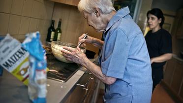 Une personne âgée prépare un gâteau sous l'oeil attentif d'une aide de vie, en Bourgogne en juillet 2011 [Jeff Pachoud / AFP]