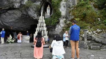 Des pèlerins prient le 15 août 2017 devant la grotte de Massabielle à Lourdes, où Bernadette Soubirous dit avoir vu des apparitions de la Vierge Marie [PASCAL PAVANI / AFP/Archives]