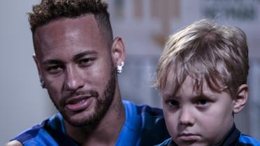 Neymar, avec son fils Davi Lucca, accorde un entretien à l'AFP, le 21 juillet 2018 à Praia Grande, près de Sao Paulo  [Miguel SCHINCARIOL / AFP]