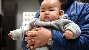 Un bébé chinois dans les bras de son père le 19 janvier 2015 à Pékin [Goh Chai Hin / AFP]