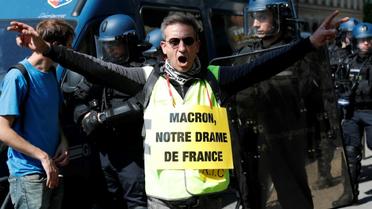 Un militant porte une pancarte avec l'inscription "Macron, notre drame français" en référence à l'incendie qui a dévasté Notre-Dame de Paris, le 20 avril 2019 [Zakaria ABDELKAFI / AFP]