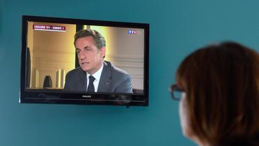 Une femme regarde une interview télévisée de Nicolas Sarkozy, le 2 juillet 2014 à Lille [Denis Charlet / AFP/Archives]