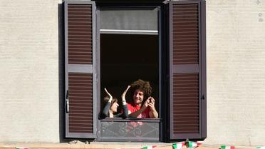 Des Italiens applaudissent depuis leur fenêtre l'assouplissement du confinement, à Rome le 3 mai 2020 [Alberto PIZZOLI / AFP]