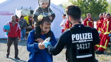 Un policier distibue de l'eau à des migrants à leur arrivée le 10 septembre 2015 à la gare de Schoeneberg près de Berlin [PATRICK PLEUL / DPA/AFP]