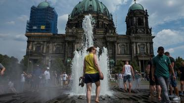 Des visiteurs se rafraïchissent dans la fontaine de la cathédrale de Berlin, le 4 août 2018 [John MACDOUGALL / AFP]