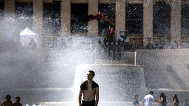 Des jeunes se rafraîchissent dans une fontaine de l'esplanade du Trocadéro à Paris, le 24 juin 2019 [Christophe ARCHAMBAULT / AFP]