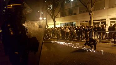 Des personnes écrivent le mot "violence" avec des bougies devant le commissariat du 19e arrondissement, le 27 mars 2017 à Paris, après la mort d'un Chinois tué par la police [Sonia BAKARIC / AFP]