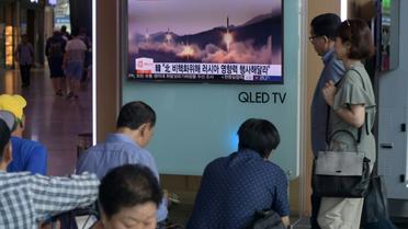 Des personnes passent devant un écran de télévision montrant des images d'archives d'un lancement de missile par la Corée du Nord à Séoul le 26 août 2017 [Ed JONES / AFP]