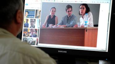 Un homme regarde une photo de l'ex-consultant du renseignement américain Edward Snowden (c) pendant sa rencontre avec des défenseurs des droits de l'homme, le 12 juillet 2013 à Moscou [- / STR/AFP]