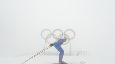 Un skieur, dans le brouillard, passe devant les anneaux olympiques à Sotchi en Russie, le 17 février 2014  [Kirill Kudryavtesev / AFP/Archives]