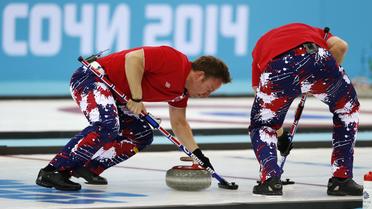 Le Norvégien Torger Nergaard (g) frotte la glace avec un balai, le 18 février 2014 lors d'une rencontre de curling contre la Grande-Bretagne à l'Ice Cube de Sotchi [Adrian Dennis / AFP]