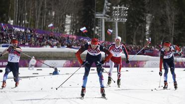 Le Russe Alexander Legkov (c) passe la ligne d'arrivée du 50 km de ski de fond et remporte la médaille d'or, le 23 février 2014 à Sotchi [Odd Andersen / AFP]