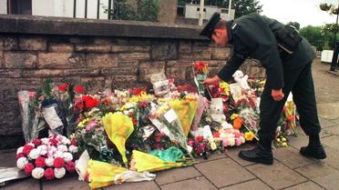 Un officier de la Royal Ulster Constabulary dépose des fleurs près du site de l'attentat d'Omagh le 17 avril 1998 [Paul Vicente / AFP/Archives]