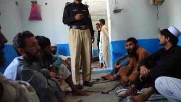 Un officier de police se tient au milieu des patients encore enchaînés de la "clinique" pour toxicomanes du mollah Ilyas Qadri, à Haripur au Pakistan, le 19 juillet 2014 [Shakil Ahmad / AFP]