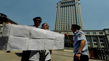 Des policiers interpellent une manifestante devant le tribunal populaire de la ville chinoise de Jinan, le 21 août 2013, à la veille de l'ouverture du procès ultrasensible du dirigeant déchu Bo Xilai [Mark Ralston / AFP]