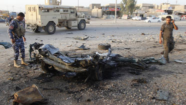 Des soldats se tiennent à côté de la carcasse d'une voiture, à Kirkouk, en Irak, le 11 juillet 2013 [Marwan Ibrahim / AFP/Archives]