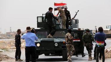 Des membres des forces anti-terroristes irakiennes brandissent le drapeau national, après avoir repris le contrôle d'un point de passage à côté de Badriyah (près de Mossoul), le 19 août 2014 [AHMAD AL-RUBAYE / AFP]